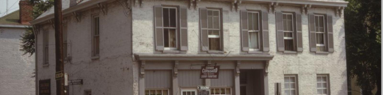 N Broadway at 2nd street gray two story building with traffic light on the left hand side of image.